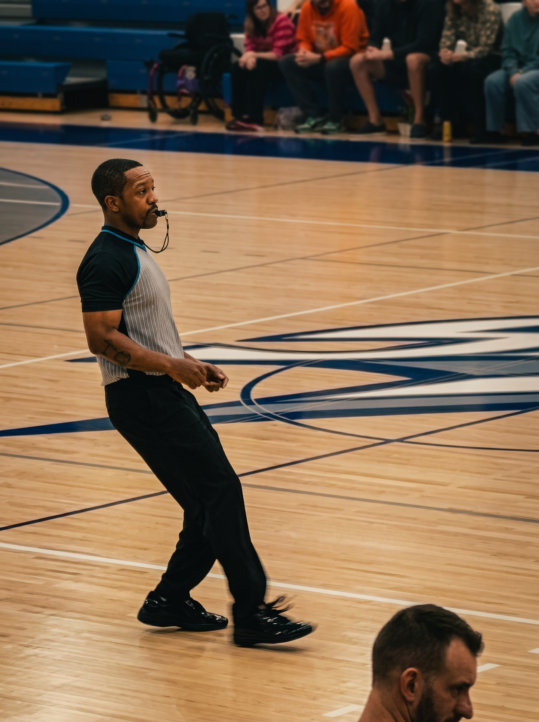 Young referee blowing a whistle on a basketball court